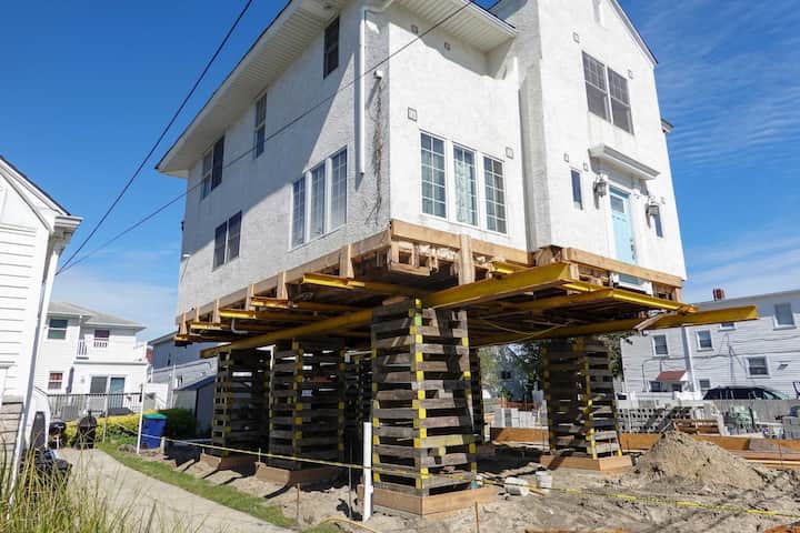 A team of professionals using specialized equipment to raise a house in Naperville, preparing it for elevation and renovation
